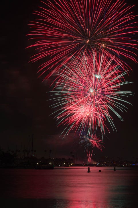red and blue fireworks erupt over body of water