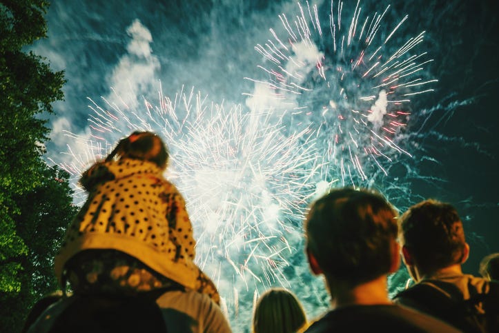 crowd of people and kids watch fireworks in the sky