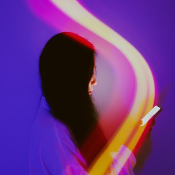 woman holding phone with abstract light over it