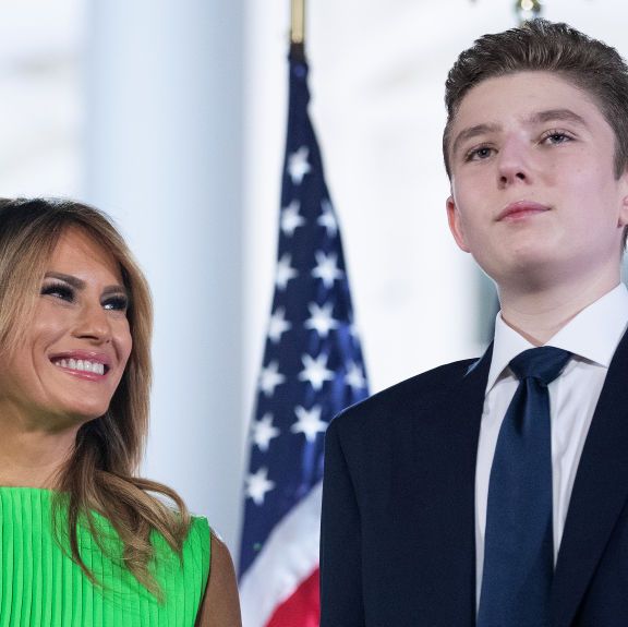 barron trump standing in front of american flags