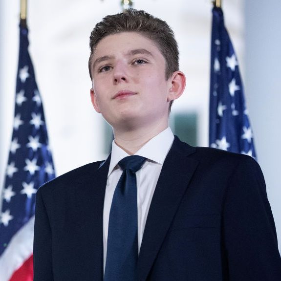 barron trump standing in front of american flags