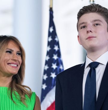 barron trump looking upward with american flags in the background