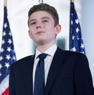 barron trump looking upward with american flags in the background