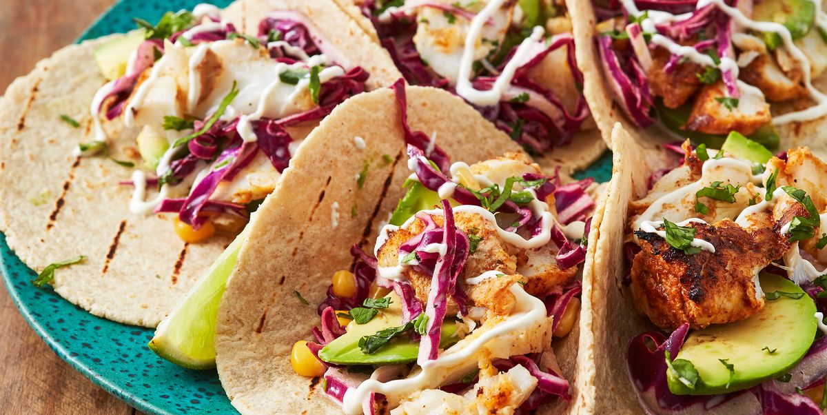 fish tacos with corn, avocado, red cabbage slaw, and sour cream drizzle on a teal plate