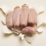 Fist punching through a ripped hole in a paper