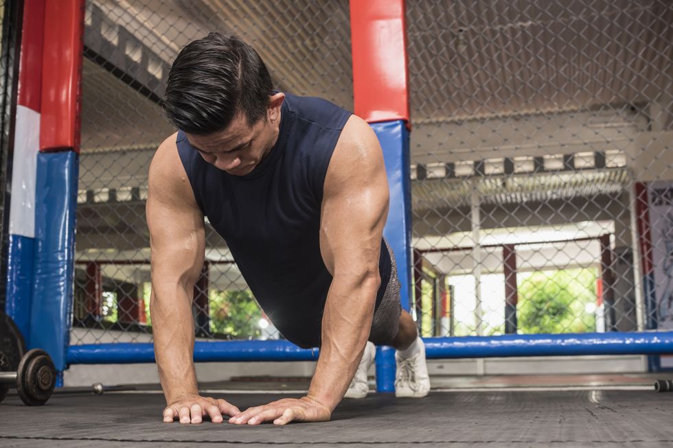 a fit asian man does diamond push ups at a mma gym body weight calisthenics or hiit workout training chest, abs and triceps
