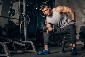 fit chinese guy practicing with dumbbell in gym