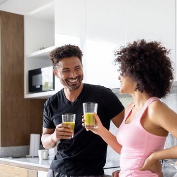 fit couple drinking a green detox juice at home
