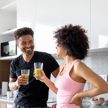 fit couple drinking a green detox juice at home