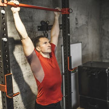 fit man doing chinups in gym man is exercising on pullup bar
