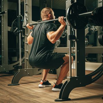 smith machine workouts fit man doing squats in a training machine