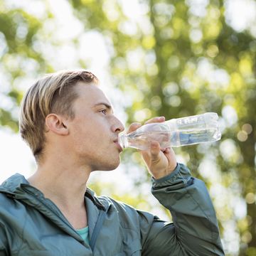 fit man drinking water outdoors