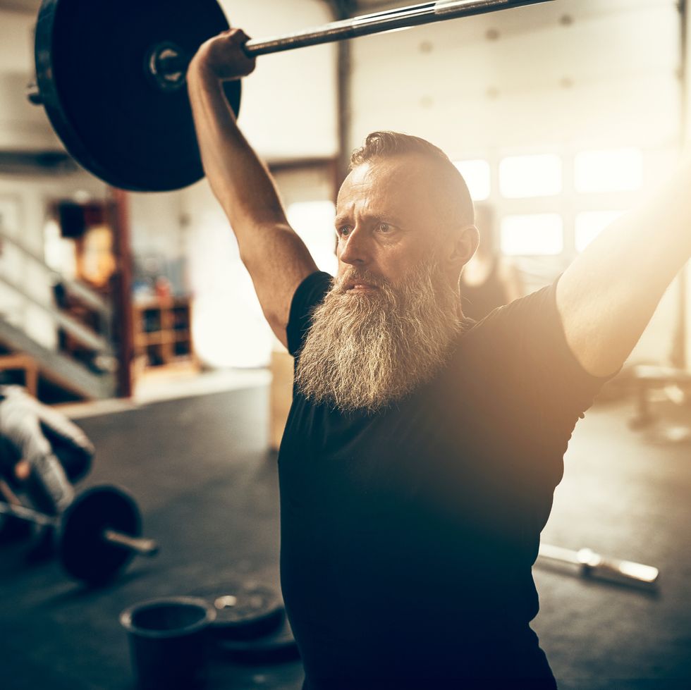 Fit mature man holding heavy weights over his head