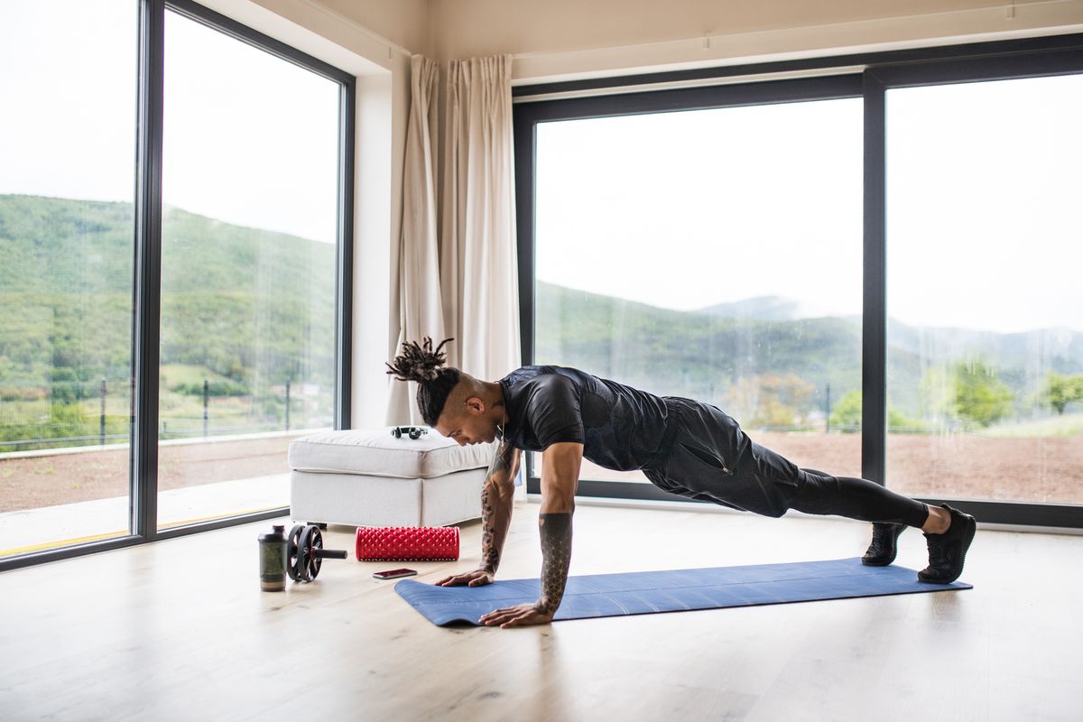 a fit mixed race man with dreadlocks doing exercise at home