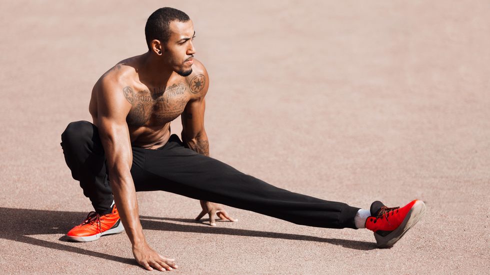 Fit shirtless black man doing stretching before workout