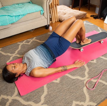 fit woman doing pelvis thrusts on floor using a skateboard