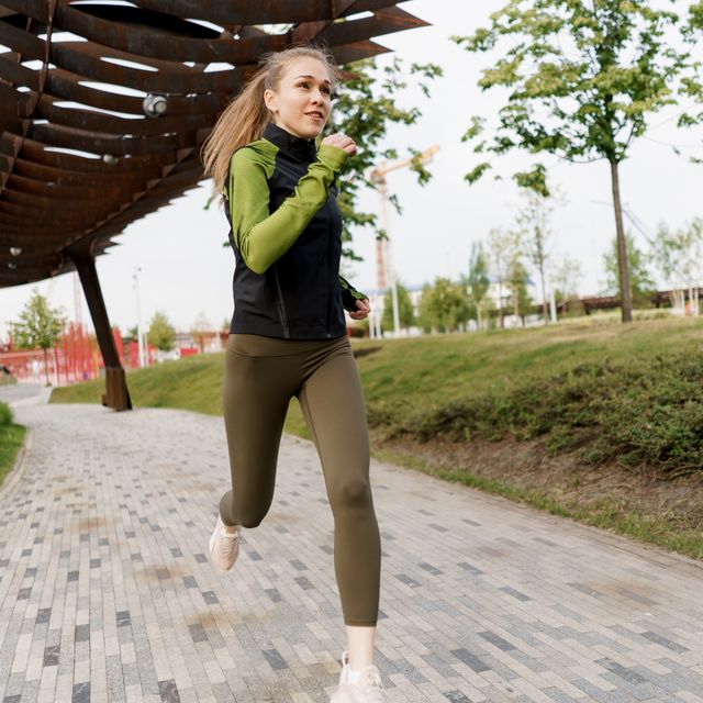 fit woman dressed in sports clothes runs in a city park