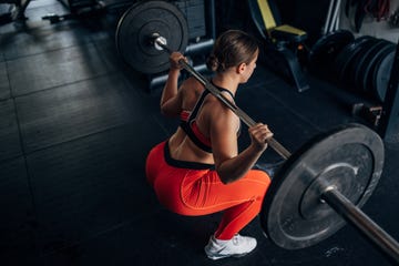 women doing barbell back squat