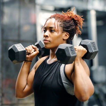 fit young african american woman working out with  and weights in a fitness gym