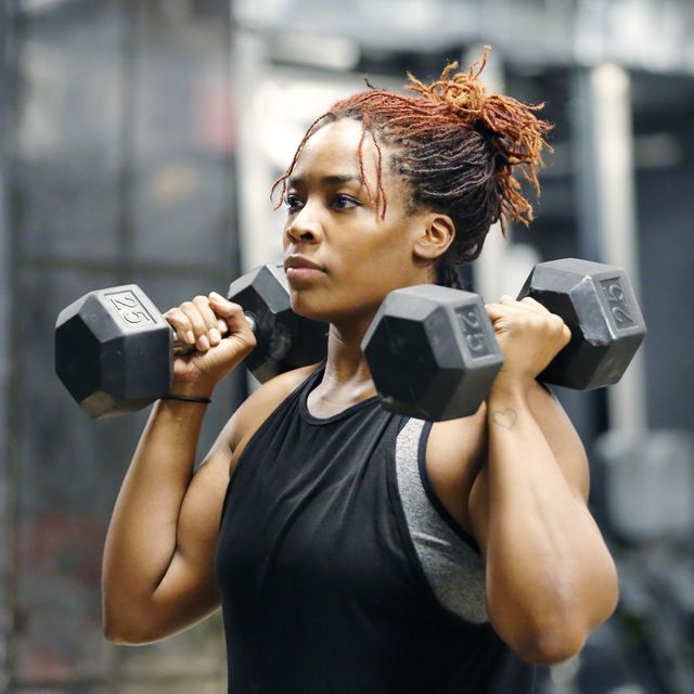 fit, young african american woman working out with hand weights in a fitness gym.