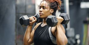 Fit, young African American woman working out with hand weights in a fitness gym.