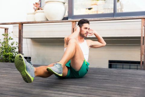 Fit young man doing crunches on floorboard