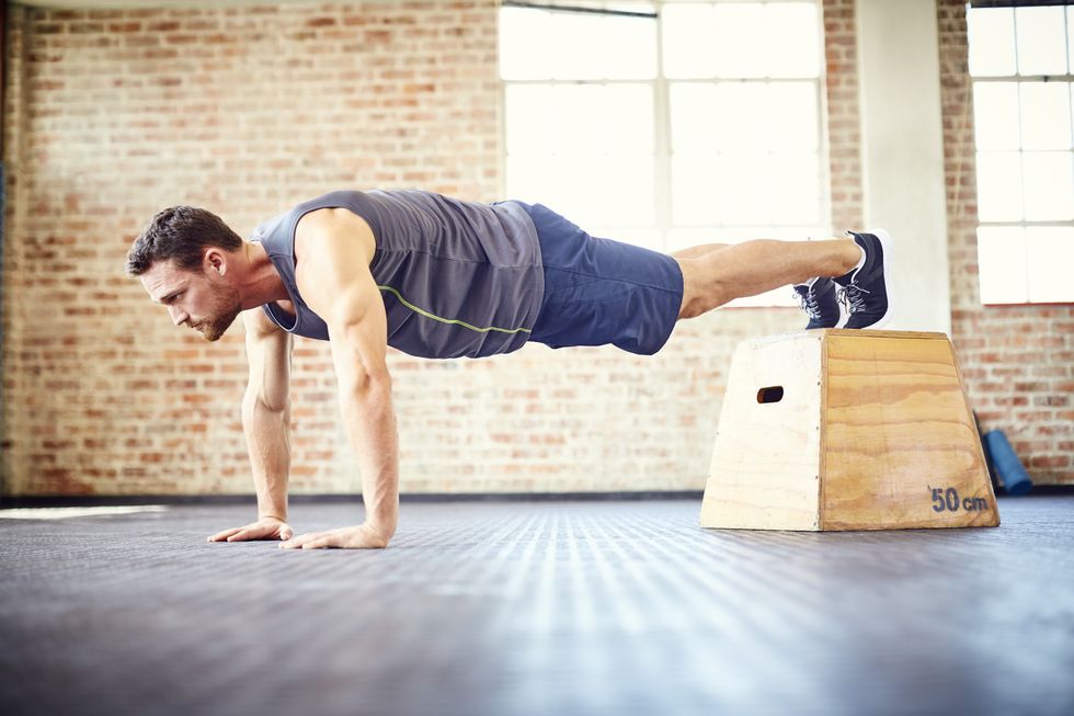 Fit young man doing push-ups on box in gym