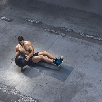 fit young man exercising indoors   doing ab exercises with a medicine ball