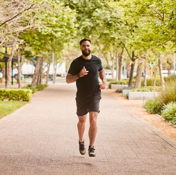 fit young man listing to music on earbuds during a park run