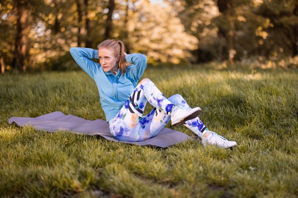 fit young woman doing bicycle crunch sit up exercise outdoors