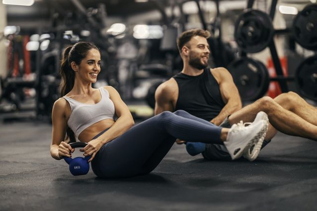 fitness couple is doing kettlebell twist in a gym togehter.