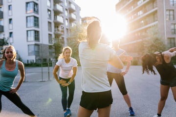 fitness instructor warming up with class outdoors