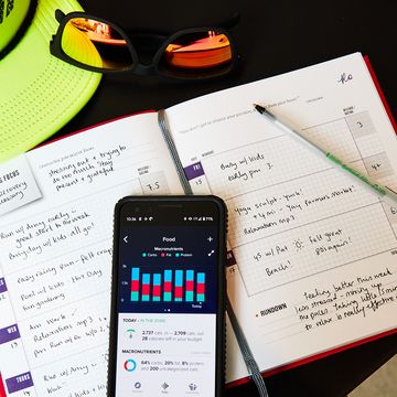 fitness journal, running hat and sunglasses with food tracker app on phone