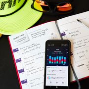 fitness journal, running hat and sunglasses with food tracker app on phone