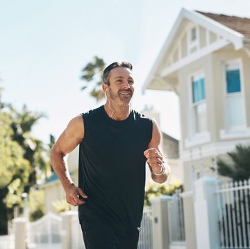 fitness, man and running in the neighborhood for exercise, health and workout on a sunny day in the outdoors happy, active and athletic male runner in sports training outside for a run by the house