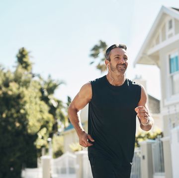 fitness, man and running in the neighborhood for exercise, health and workout on a sunny day in the outdoors. happy, active and athletic male runner in sports training outside for a run by the house