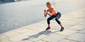 fitness model young and strong blonde woman in sports clothing exercising with a resistance band outdoors in front of the river