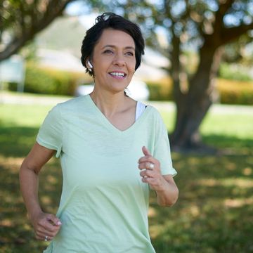 fitness, park and mature woman running for healthy body, wellness and cardio workout outdoors freedom, sports and middle aged female listening to music for exercise, training and active lifestyle