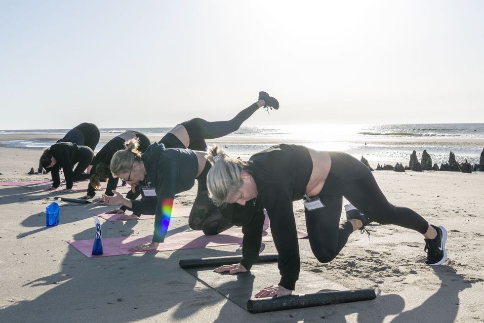 a group of people doing push ups on a beach