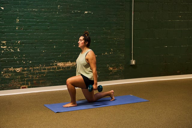woman doing weighted lunges in a gym