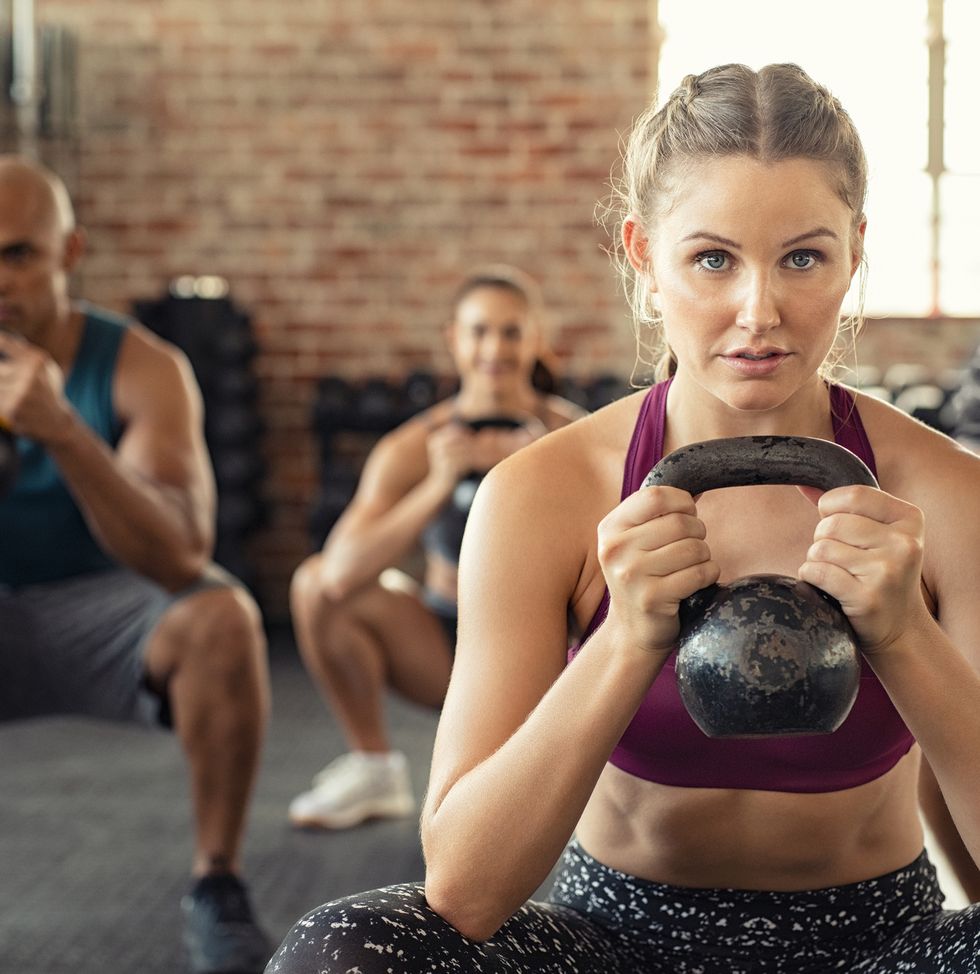 Fitness woman squatting with kettle bell