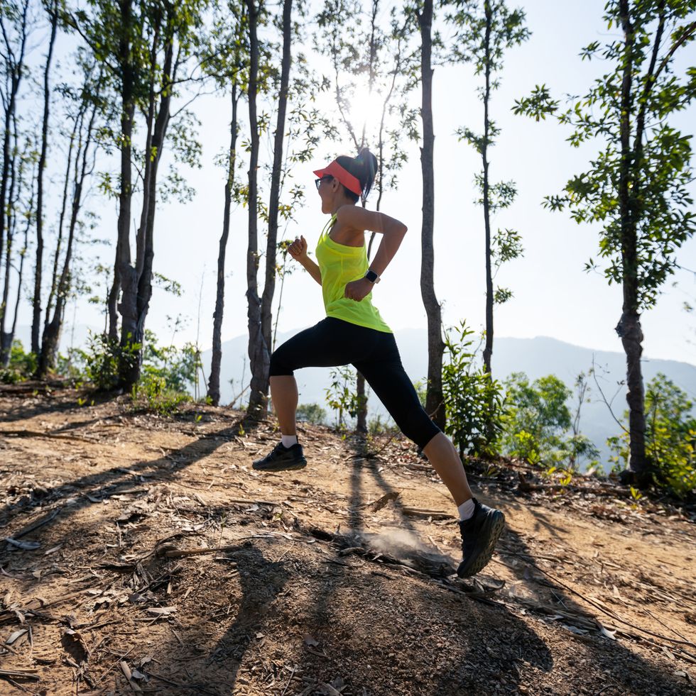 fitness woman trail runner running on sunrise tropical forest mountain peak