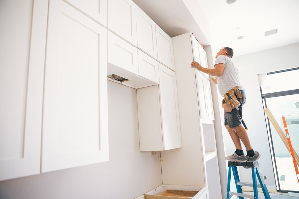 a man installs cabinet doors in a kitchen