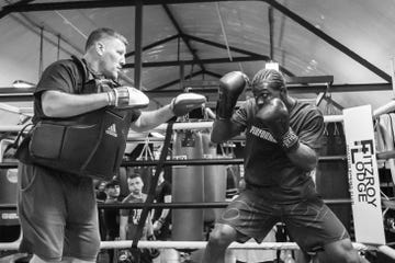 Boxing training session featuring a trainer and a boxer in gloves