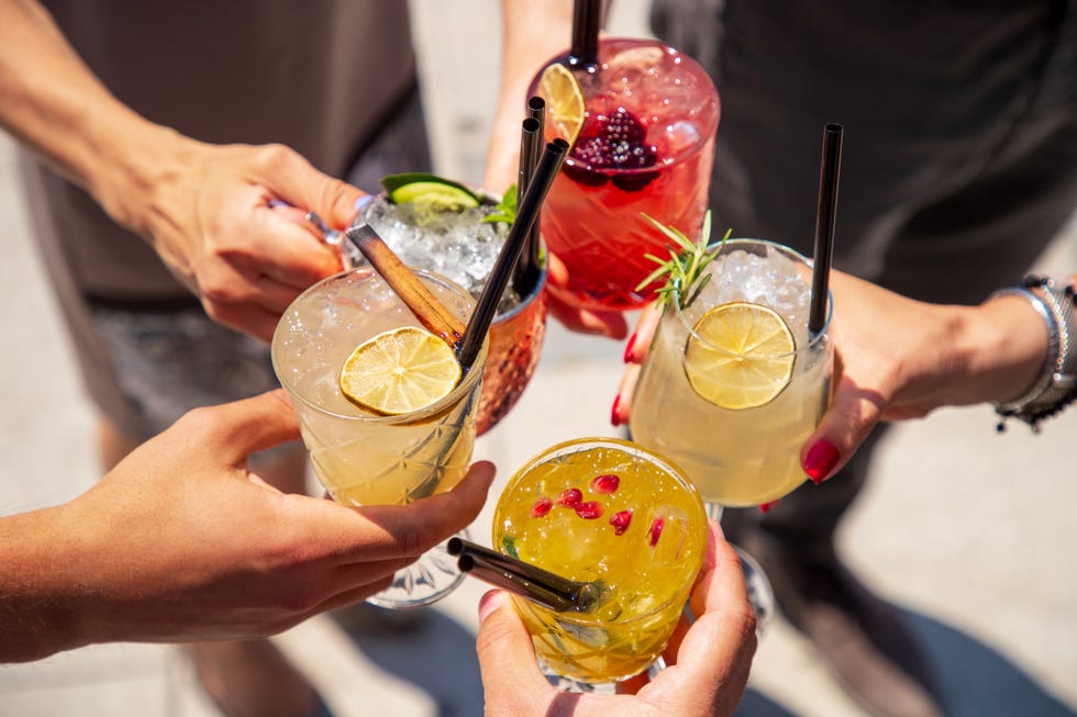five cocktails in hands joined in celebratory toast