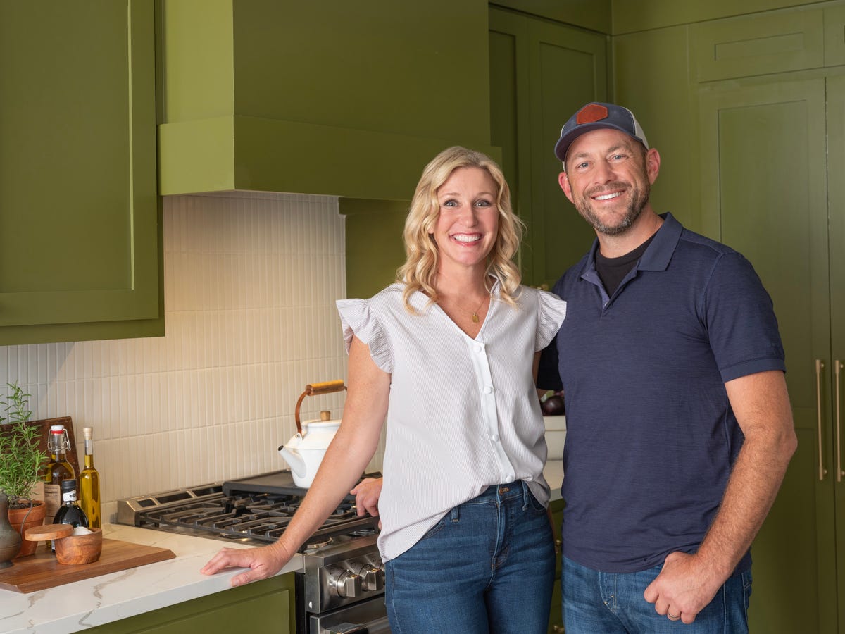 couple standing together in a modern kitchen with dark green cabinetry