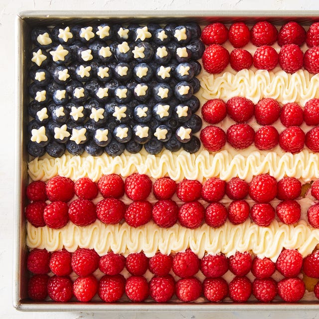 cake topped with raspberries, icing, and blueberries to create an american flag design
