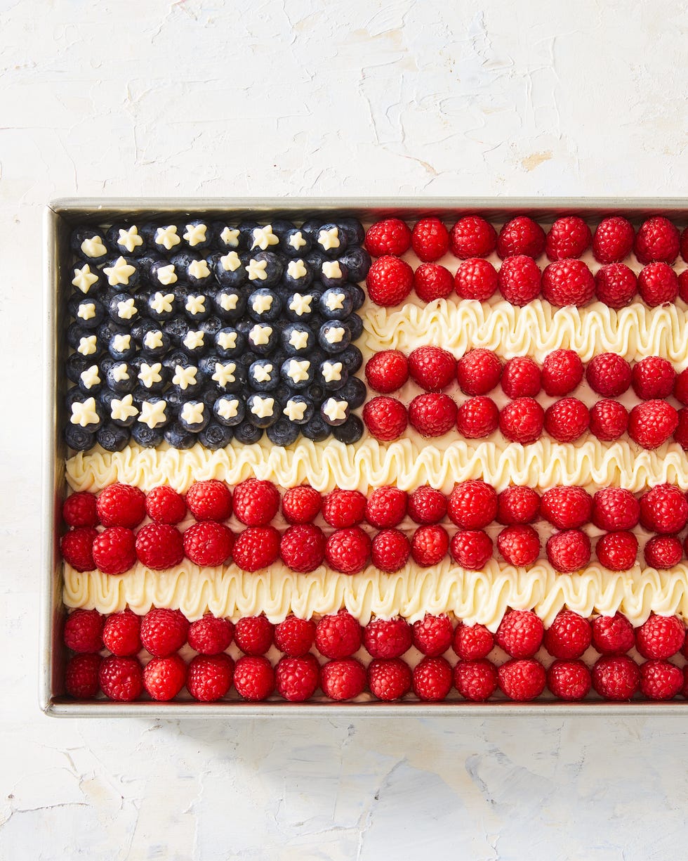 cake topped with raspberries, icing, and blueberries to create an american flag design