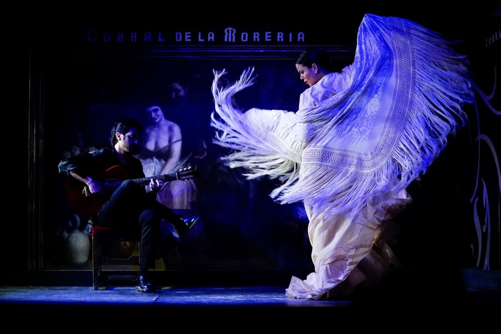 a woman dancing in a white, fringed cape