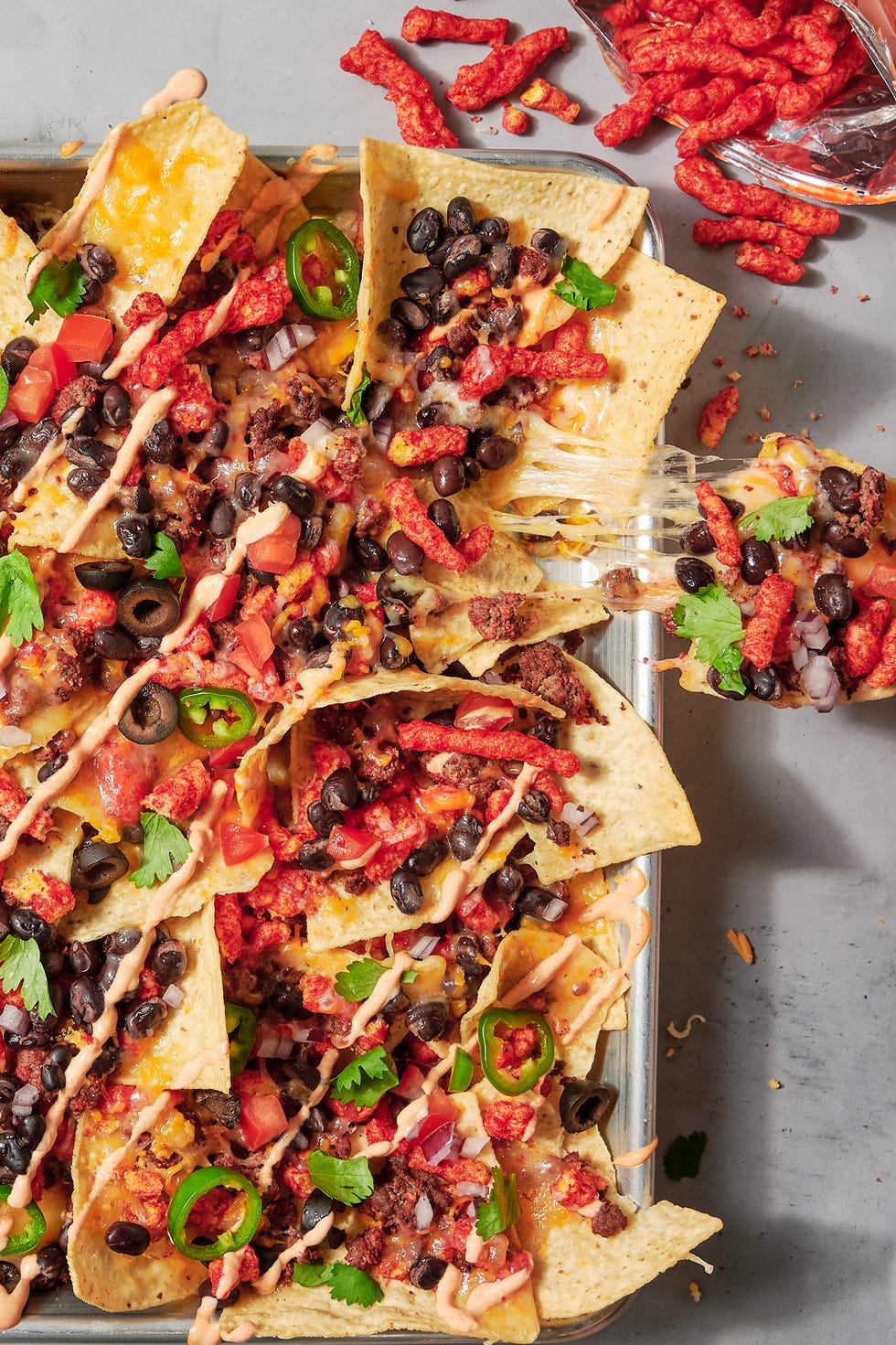 nachos topped with flaming hot cheetos, black beans, jalapenos and cilantro